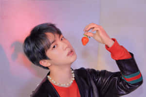 穿著皮褸的年輕男子在攝影棚中將草莓靠近臉部 — 成振宇 壁紙