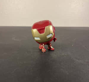 紅色和金色的鐵甲奇俠 Funko Pop 人偶，在深色有刮痕的表面上。 — 鐵甲奇俠標誌 壁紙