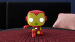 紅色和金色的鐵甲奇俠Funko Pop人偶，在黑色沙發附近的紅色紋理表面上。 — 鐵甲奇俠標誌 壁紙
