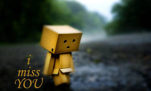 一個黃色紙箱角色站在雨中，帶有文字 i miss YOU — 傷感語錄 壁紙