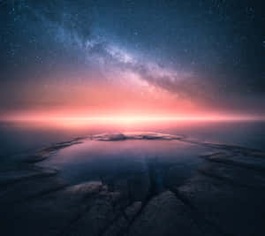 岩石地形上反射池上方有粉紅色地平線的星空。 — Nokia 壁紙