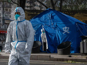 穿著防護裝備的醫護人員在城市街道上靠近藍色應急帳篷行走。 — 唐人街 GIF 壁紙