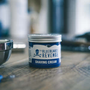 Bluebeards Revenge 剃鬚膏罐放在木質枱面上，旁邊有金屬碗 — 1:1 壁紙