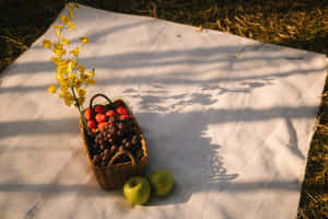 斑駁陽光下，草地上白色布上的草莓、葡萄和蘋果籃子。 — MacBook Pro 壁紙
