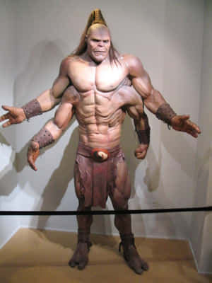 一個栩栩如生的蠟像，展示一位身穿部落裝備的肌肉戰士，陳列於博物館中。 — Kindle 壁紙