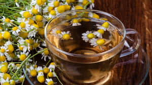 玻璃杯中的洋甘菊茶與木桌上的鮮花 — 青綠色 GIF 壁紙