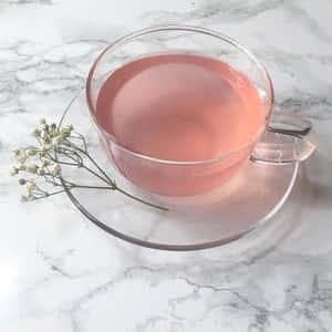 一個玻璃茶杯，裝有粉紅茶和乾燥滿天星，放在大理石檯面上。 — 1:1 壁紙