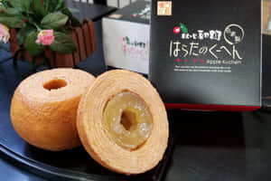 金色蘋果庫亨糕點，閃亮餡料，旁邊有黑色盒子和粉紅色花。 — 糖果 GIF 壁紙