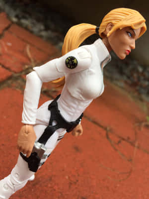 金髮動作公仔著白色S.H.I.E.L.D.制服蹲喺紅色磚上面。 — Galaxy Z TriFold 壁紙