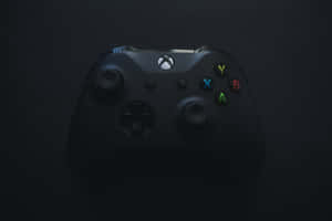 黑色Xbox手掣在深色背景上帶有發光按鈕 — MacBook Pro M3 壁紙