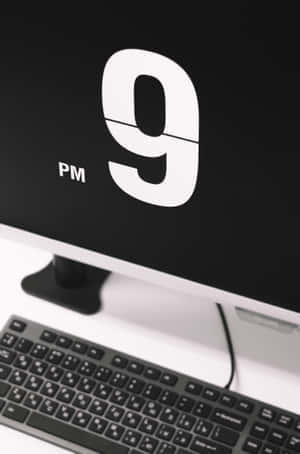 電腦顯示器顯示晚上9點，下方有鍵盤在白色桌子上 — 小米Pad 9 Pro 壁紙