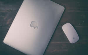 深色木桌上的銀色 MacBook 和滑鼠