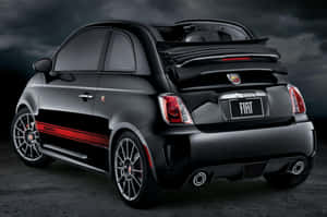 暴風雨天空下的黑色Fiat 500 Abarth跑車，帶有紅色條紋。 — Surface Laptop 壁紙