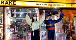 女子和機械人雕像在設有玻璃展示櫃的動漫店外舉起拳頭。 — 可愛動漫頭像gif 壁紙
