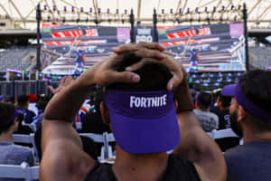 戴著紫色Fortnite帽子的粉絲在遊戲活動中沮喪地抱著頭。 — 遊戲 壁紙