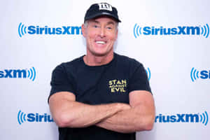 戴帽子和T恤的男子在SiriusXM活動中微笑交叉雙臂。 — 康納·麥格雷戈 壁紙