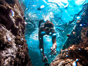 浮潛者探索岩石水下峽谷，陽光穿過海水過濾。 — 水下 壁紙