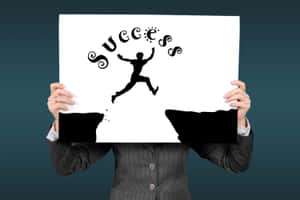 穿西裝的人手持帶有跳躍人物和 success 字樣的標牌 — 勵志語錄 壁紙