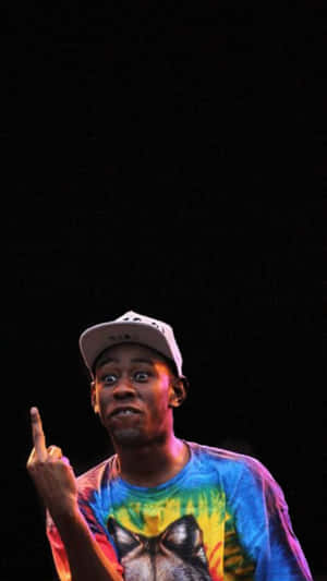 身穿紮染襯衫的男子在舞台上燈光下向上指 — Tyler the creator GIF 壁紙