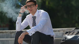 戴眼鏡的年輕男子在戶外混凝土台階上抽煙。 — 吸煙 壁紙
