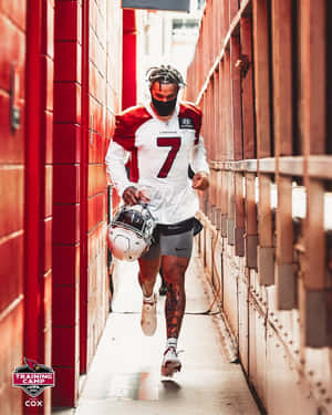 身穿 Cardinals 球衣的足球員手持頭盔跑過紅磚隧道。 — NFL 美式足球 GIF 壁紙
