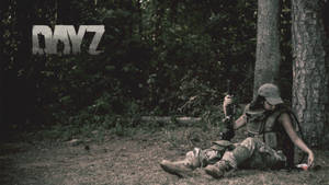 一名身穿迷彩裝備的士兵在森林中靠著樹休息，手持步槍。 — Dayz GIF 壁紙