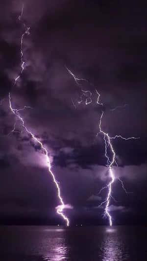 兩道強勁的閃電照亮了水面上黑暗的暴風雨之夜。