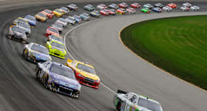 NASCAR賽車在日落時分繞著彎道飛馳。 — 賽車 壁紙