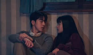 年輕情侶在燈光昏暗的房間裡緊貼著坐在條紋沙發上。 — 情侶 GIF 壁紙