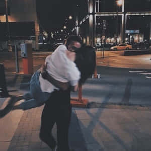 一名男子在夜間的城市行人道上熱情地抱起一名女子擁抱。 — 可愛情人節gif 壁紙