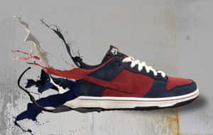 一對紅色和海軍藍色的Nike Dunk波鞋，在灰色牆壁上帶有油漆飛濺效果。 — MacBook Pro 16 壁紙