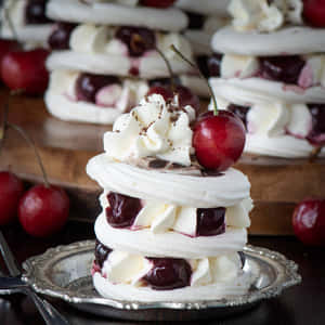銀盤上堆疊的蛋白酥皮甜點，配以鮮奶油和櫻桃。 — 甜牙 GIF 壁紙