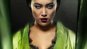 擁有引人注目的眼睛和紅唇的女性，背景是綠色窗簾。 — 武士 壁紙