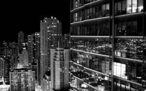 夜晚城市的黑白照片，有明亮的摩天大樓和玻璃反射。 — 城市景觀 壁紙