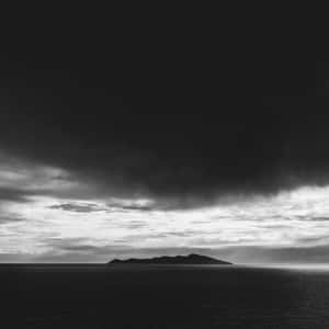 在黑暗暴風雨的天空下，一個小島孤獨地矗立在海洋中。 — 雷暴 壁紙