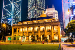 在繁華的城市景觀中，夜晚被照亮的歷史建築。 — MacBook Air M2 壁紙