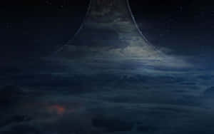 一座高聳的宇宙山峰在繁星點點的夜空下升起於雲層之上，伴隨著發光的星雲。 — 2880x1800 壁紙