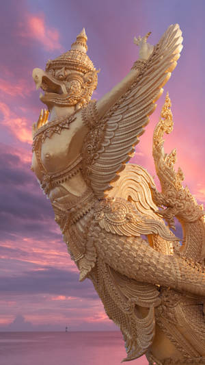 金色迦樓羅雕像在海洋上空的日落中 — 淺粉紅色美學動圖 壁紙