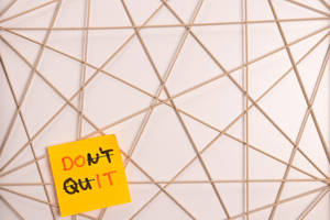 黃色便利貼，上面有「DON'T QUIT」訊息，背景為金屬網格。 — 鼓舞人心的 壁紙