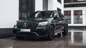 黑色Mercedes-AMG GLC 63 S SUV停在濕路面上，帶有建築物倒影。