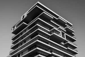 從下方仰望的現代高層建築，帶有階梯式陽台，黑白風格。 — 建築 壁紙
