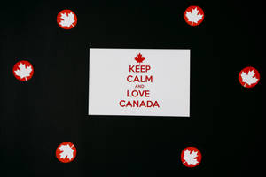 白色卡片，紅色文字寫著 Keep Calm and Love Canada，周圍是紅色楓葉貼紙。 — 語錄 壁紙