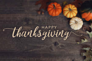 木桌上擺放南瓜和秋葉，並有 Happy Thanksgiving 文字。 — MacBook Pro 16 壁紙