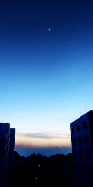 暮色中城市建築物上的月亮 — 藍天 壁紙