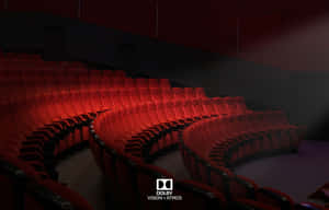 在黑暗的影院中，帶有 Dolby Vision Atmos 品牌標識的紅色電影院座椅排。 — MacBook Pro 壁紙