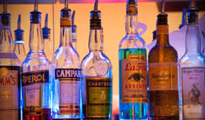 夜間酒吧架上被霓虹燈照亮的色彩繽紛酒瓶。 — 溫暖 壁紙