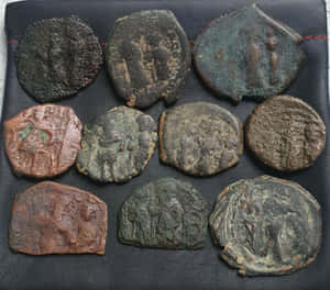 一系列古代腐蝕硬幣，帶有褪色雕刻，在深色紋理表面上。