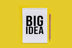 黃色背景上帶有「BIG IDEA」文字和鉛筆的白色筆記本 — 黑色動態圖 壁紙