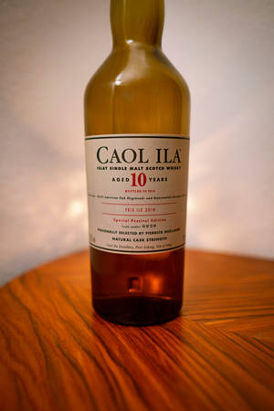 一瓶 Caol Ila 10 年威士忌放在木桌上。