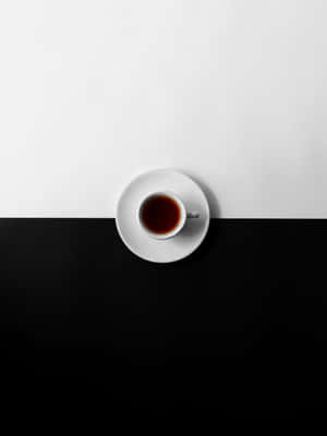一個白色茶杯裝著深色液體，放在碟子上，背景為黑白兩色。 — 2048x2732 壁紙